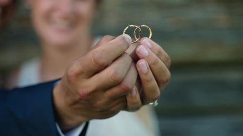 Pareja de novios sosteniendo anillos juntos