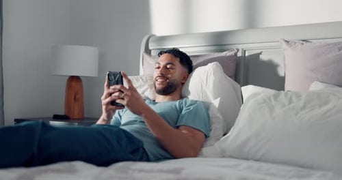 Man Relaxing in Bed Using Smartphone