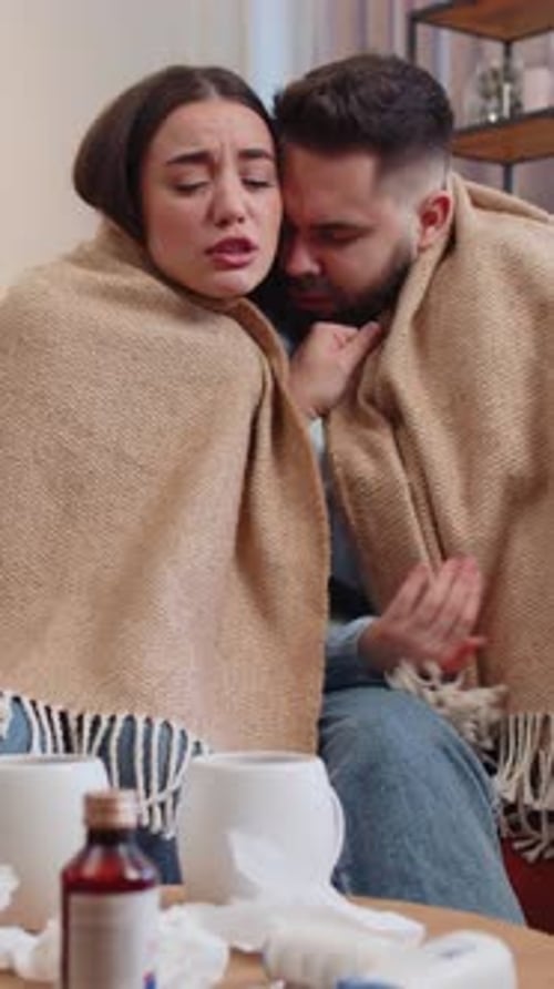 Ill Couple Covered with Blanket Blows Nose Indoors