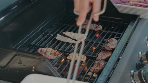 meat grilling over open flames on a well used backyard barbecue