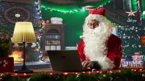 Santa Claus Using Laptop at Decorated Desk