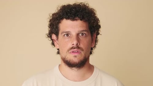 Close-up of amazed man looking at camera expressing wow in studio on beige background