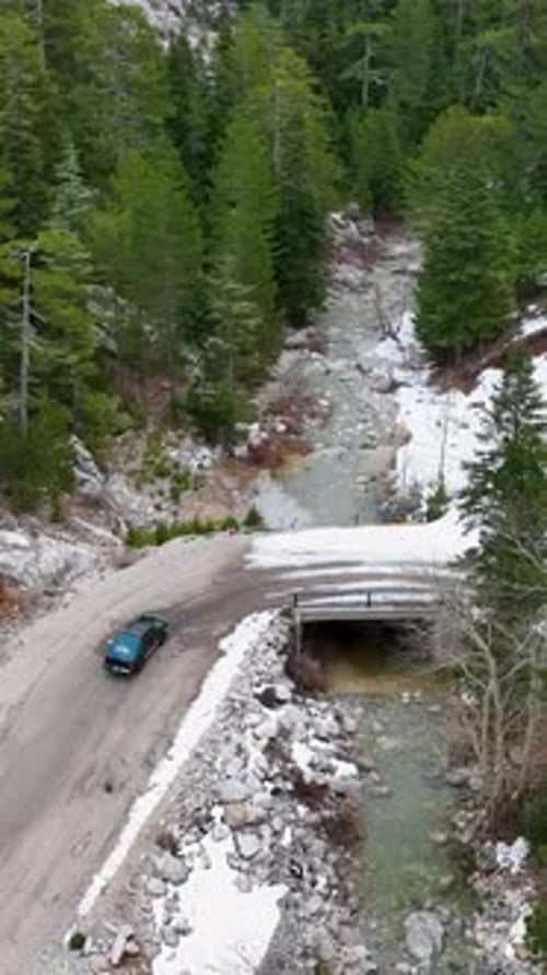 Vertical Video Aerial Winter Escape Pickup Truck Journey on Snowy Road Through Green Forest