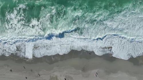 Vidéo aérienne Les vagues de tempête ondulantes laissent des motifs de mousse complexes sur la côte sablonneuse