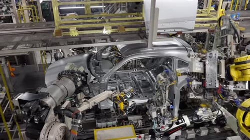Des robots soudent la carrosserie de la voiture.