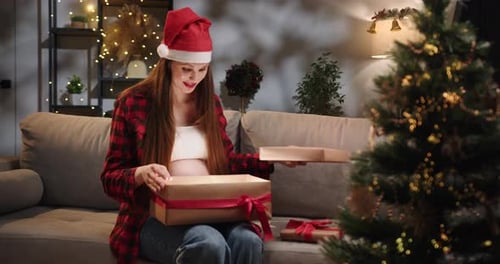 Pregnant Woman Opening a Christmas Gift at Home