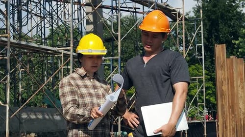 Construction manager and engineer discussing and checking plans on construction site.