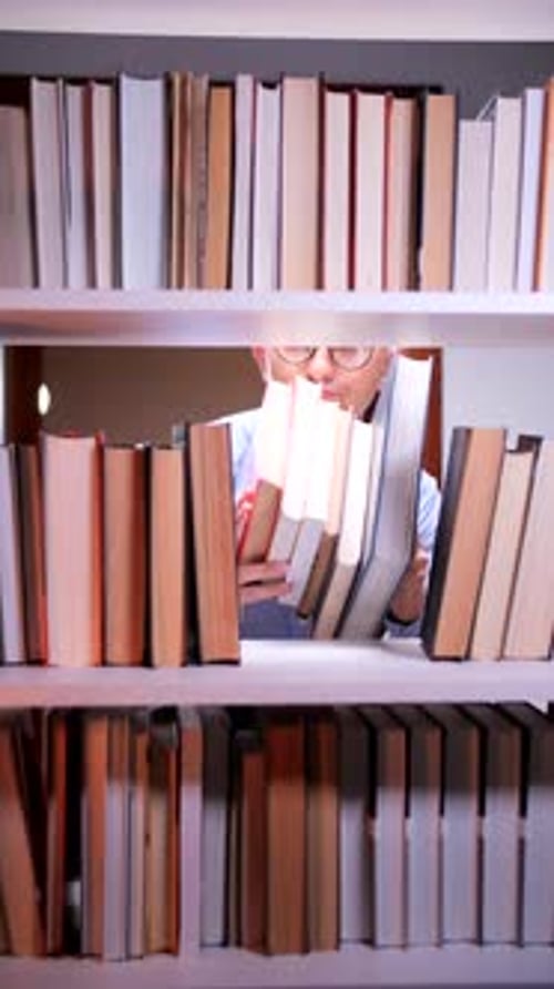 Young Adult Looking at Books on Bookshelf