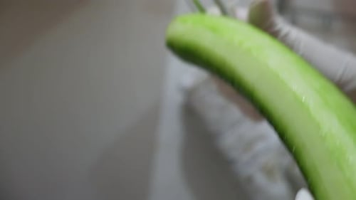 A cucumber is peeled with a potato peeler