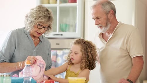 Grandparents Preparing School Lunch with Granddaughter in Kitchen