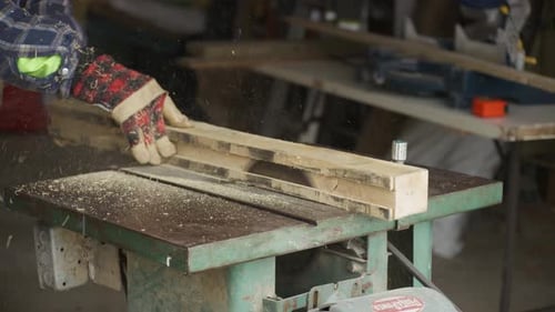 Un homme coupe un morceau de bois à l'aide d'une scie circulaire à table.