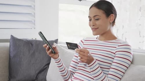Woman Using Phone and Credit Card to Shop Online