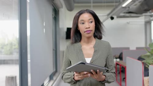 African american businesswoman using digital tablet while walking in office