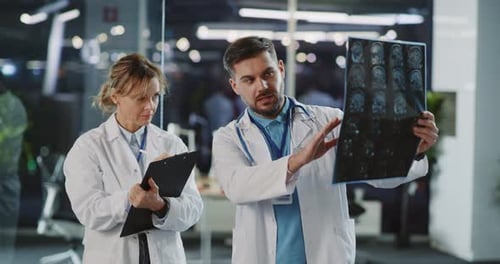 In Modern MRI Office Environment Young Caucasian Professional Doctor Teaching Female Interne Showing