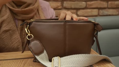 Woman opening a fashionable brown leather purse