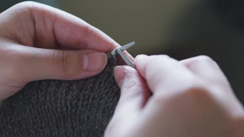 Hands Knitting Gray Yarn with Silver Needles