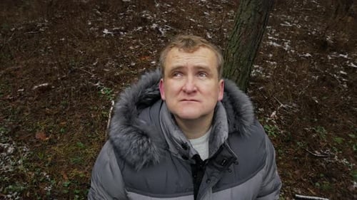 Middle aged man walking and looks birds at the winter pine forest close-up