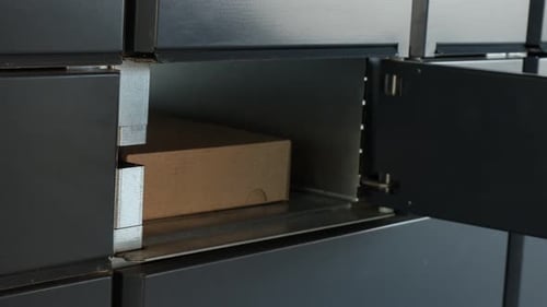 Man taking out cardboard box from parcel locker outdoors, closeup