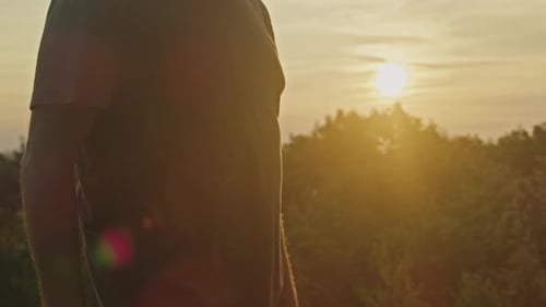 Man Spraying Mosquito Repellent on Mountain at Sunset
