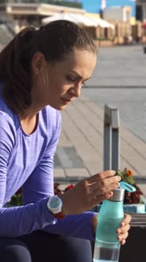 Thoughtful Woman Sipping Water on a Branch Enjoying a Serene Urban Moment