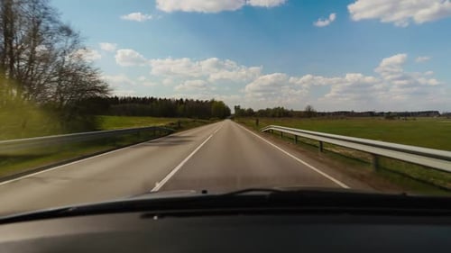 A Vehicle Travels on Asphalt Road Under Sunny Sky