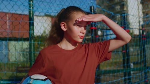 Girl Holding Soccer Ball Looking to the Distance