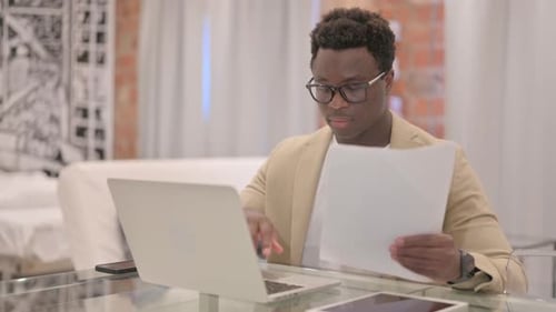 Young Adult Works with Laptop and Document