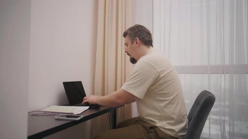 Man Working on Laptop at Desk Indoors Daytime