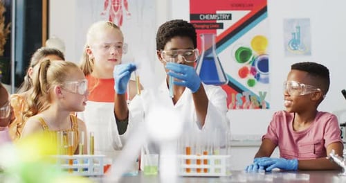Diverse female teacher and happy schoolchildren having science class in school lab