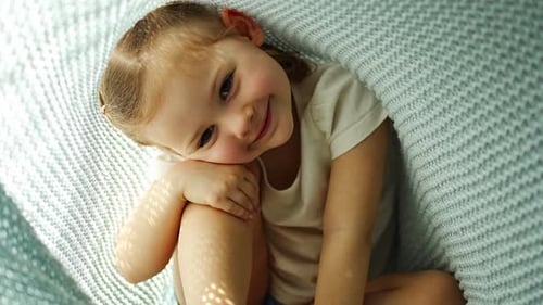 Little Girl Have a Fun Under Blue Knitted Plaid in Sunny Morning