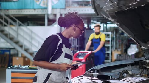 Female Mechanic Uses Tablet Inspecting Car Engine