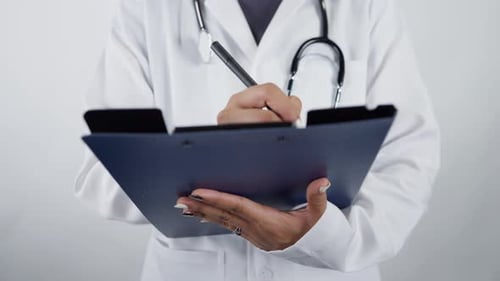 Doctor Writing on Clipboard in Hospital Close Up