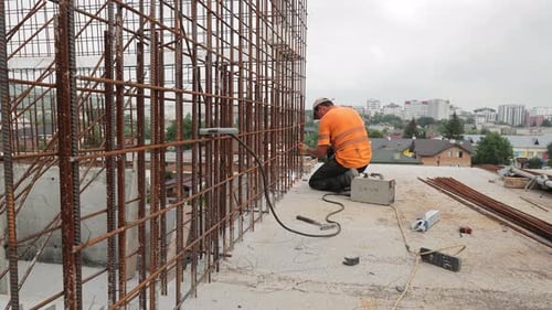 Der Schweißer auf der Baustelle schweißt die Metallkonstruktionen des monolithischen Fundaments von