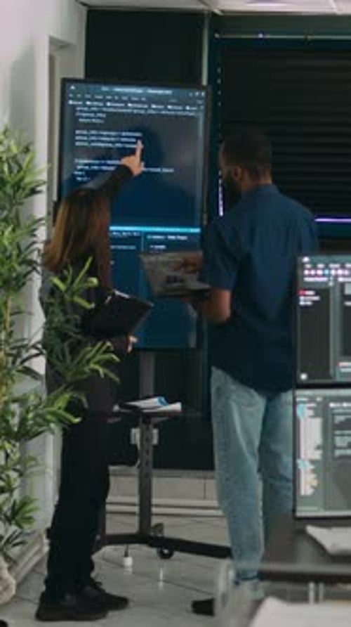 Vertical Video Diverse Team of System Developers Analyzing Code on Big Tv Screen
