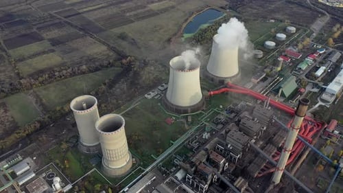 Aerial view of abandoned cooling towers of the coal power plant. Smoke rising above the plant