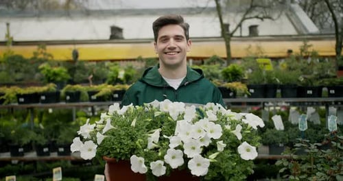 Botanical Beauty Smiling Florist Holding Plants in Green Uniform at Specialized Store