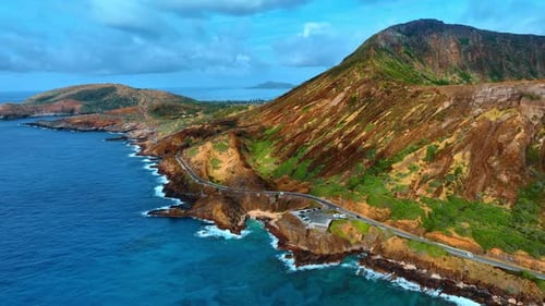 View on the road crossing the rocky shore of the Pacific Ocean. Volcanic mountains of Oahu