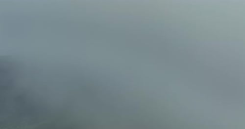 Flying trough white fluffy clouds above green mountain peaks. Beautiful summer sunny day on the high