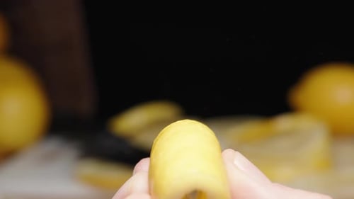 Lots of Sliced Lemon in the background. I squeeze a lemon peel in my hand and the juice splashes aro