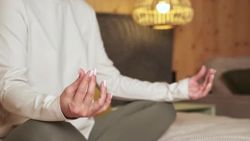 Woman Meditating Indoors on Bed in Lotus Position