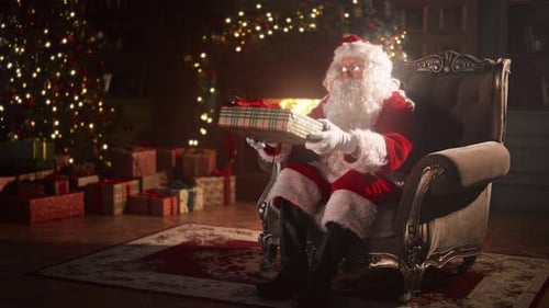 Santa Claus Holding Present Sits in Chair