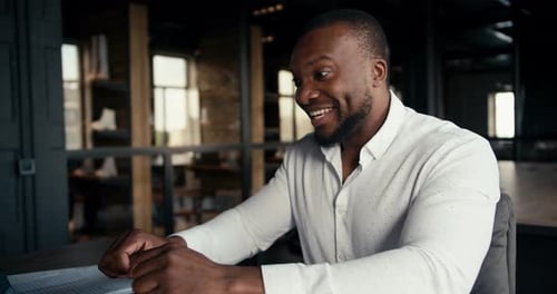 Un homme à la peau noire et vêtu d'une chemise blanche se réjouit de son succès au bureau Un employé de bureau travaille dans un