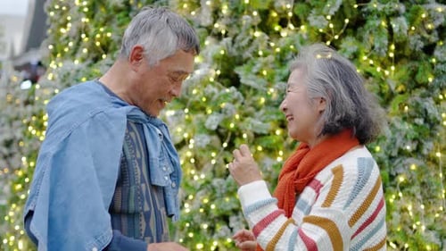 Senior Couple Laughing and Dancing Near Christmas Tree