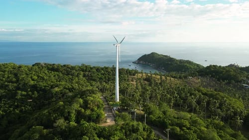 Aerial of isolated windmill wind turbine for renewable clean green energy supply on top of green hil