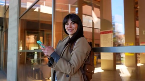 Smiling university student texting on smartphone