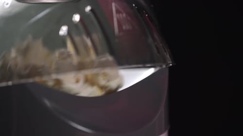 Close up: Fluffy fresh popcorn snack exits hot air popper against black background.