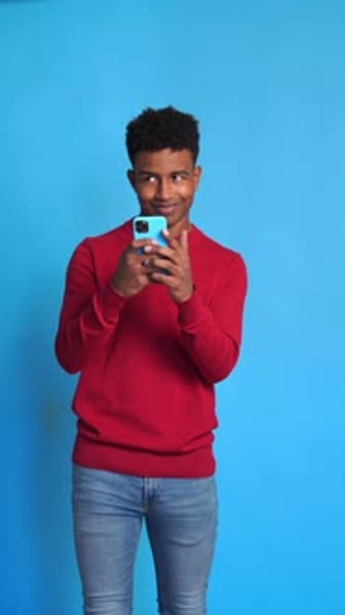 Young Adult Using a Phone on Blue Background