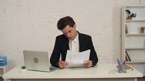 Medium Video of a Young Man Sitting in the Office Cheching the Graphs and Charts on His Table He Has