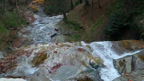 High angle view of a beautiful waterfall cascading down into a creek in an autumn forest.