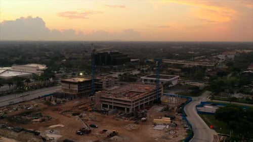 Un timelapse aérien d'un chantier de construction lors d'un lever de soleil doré en Floride. Le camion-caméra avec Drone